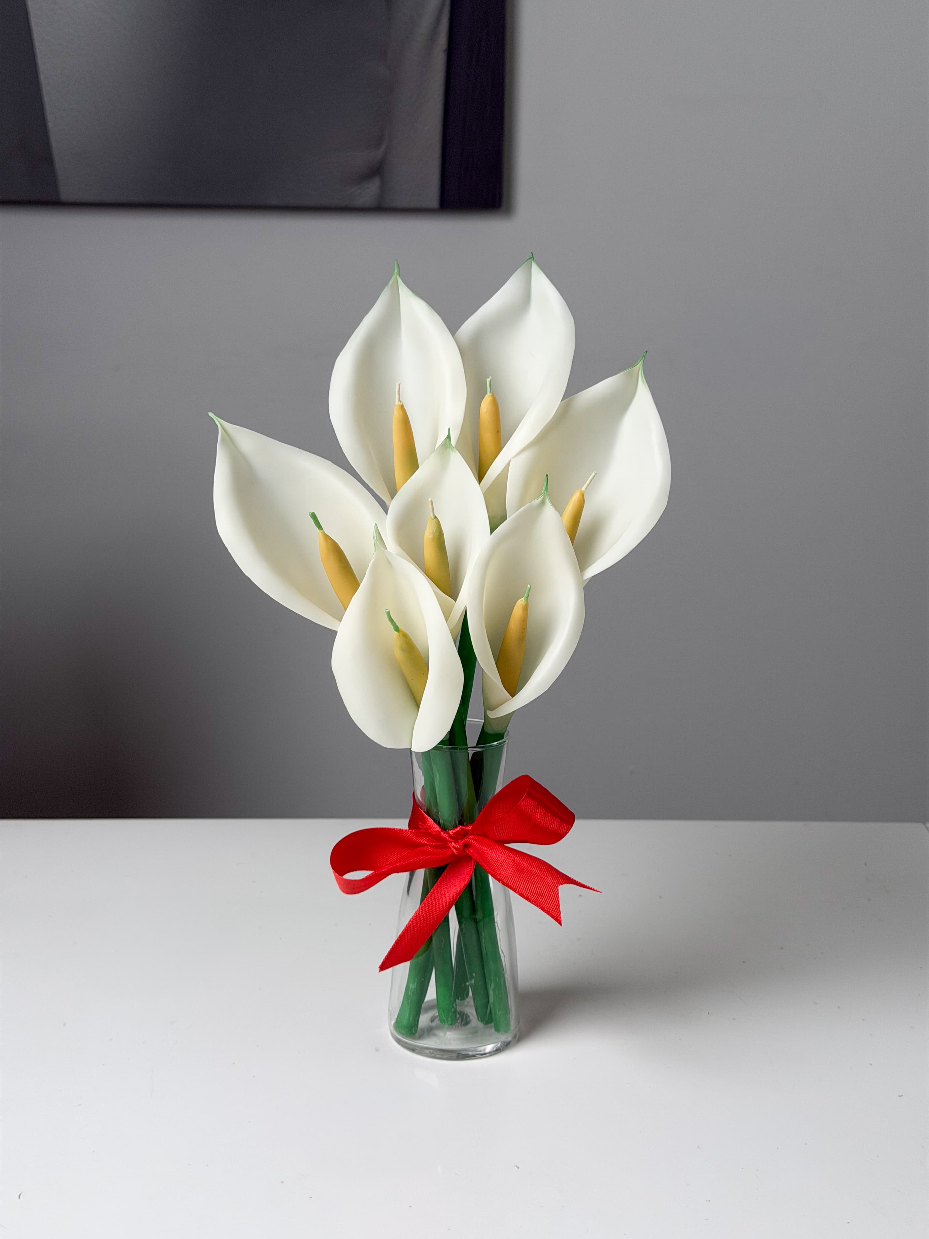 White calla lily candle bouquet with a red ribbon